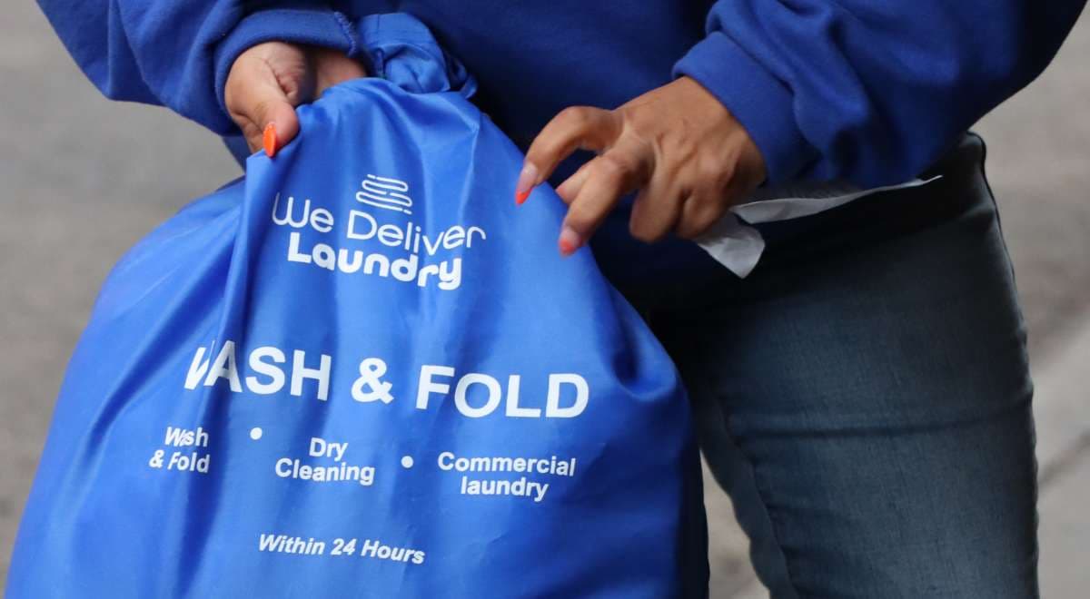 We Deliver Laundry branded bag at an NYC apartment door ready for pickup
